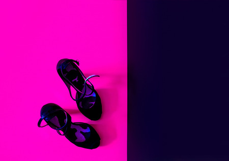 Black velvet shoes in neon light. Contrast bright background. Toned photoの写真素材