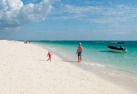 Zanzibar, Tanzania - July 13, 2018: Father and daughter spend time on the beautiful Kendwa beachのeditorial素材