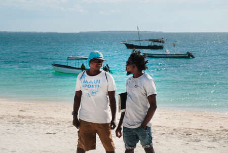 Zanzibar, Tanzania - July 13, 2018: Two attractive African guys provide touristically services and excursions activities on a beachのeditorial素材