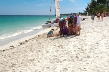 Zanzibar, Tanzania - July 13, 2018: Children from different cultures playing with sand on the beach on a sunny dayのeditorial素材