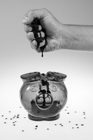 Blood is dripping from a hand into the moneybox with grey and white gradient backgroundの写真素材