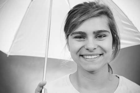 Teenager girl with an umbrella looking into the camera and laughing.の写真素材