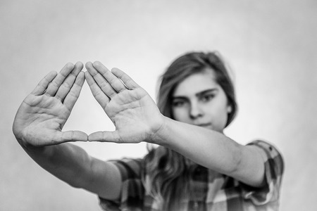 Young teenage girl is showing the Illuminati triangle symbol. White background behind her.の写真素材