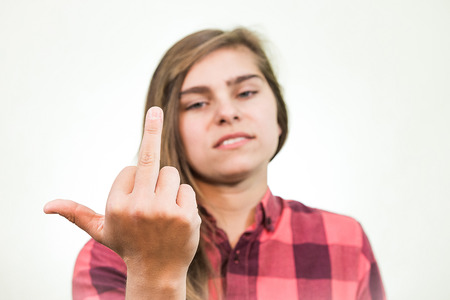 Young teenage girl is showing a middle finger with the manner of disrespectの写真素材