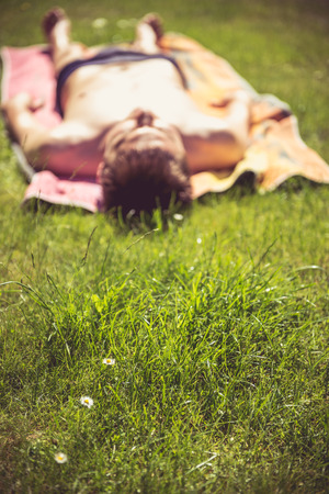 Photo of a young man that is sunbathing. A lot of greenery in the foregroundの写真素材