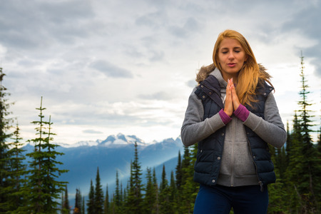 Beautiful girl meditation among mountainous landscape