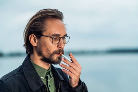 Photo of a young man lighting up a cigarrete