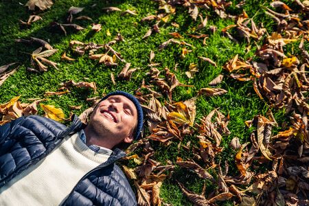 Happy young man relaxing in the park among autumn leaves.の写真素材
