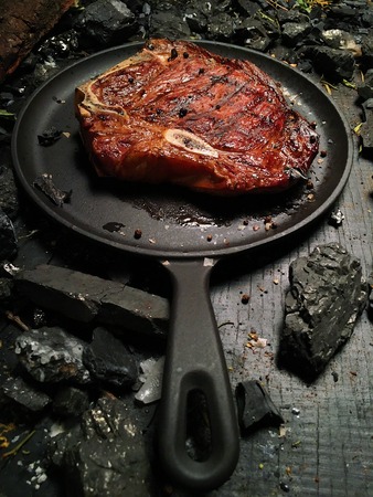 Appetizing juicy steak lies on a frying pan.の写真素材