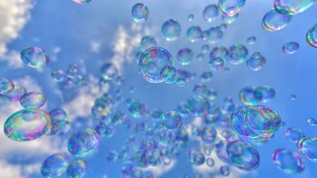 Vibrant soap bubbles floating against a simple blue sky.の写真素材
