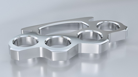 Chrome knuckle duster in a simple studio environment on a reflective surface.の写真素材