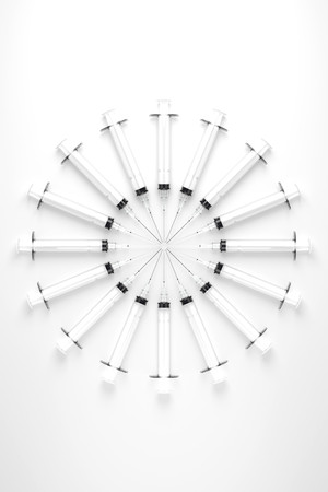A circular array of inwardly pointing hypodermic needles on a slighly reflective white surface.の写真素材