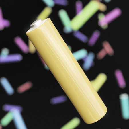 Yellow triple-A battery floating against a background of like objects in different colors in an...