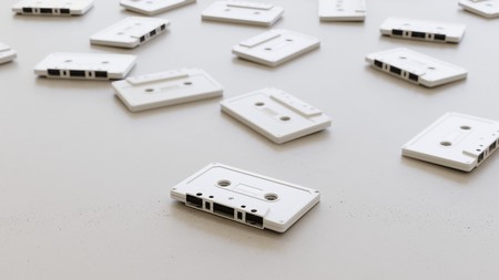 Large scattered array of white cassette tapes arranged on a minimally textured white concrete surface. This image is a 3d rendering.の写真素材