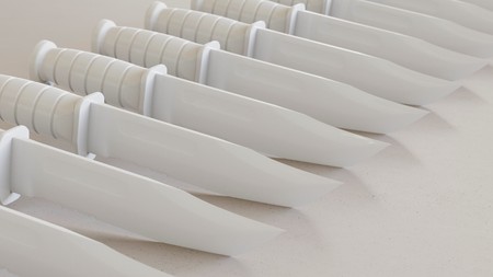 Close up on a tightly packed, perfectly aligned linear array of variously colored Plastic Toy Hunting Knives on a simple modernist neutral surface. This image is a 3d render.の写真素材