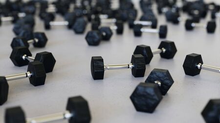 Large scattered array of black dumbells arranged on a minimally textured white concrete surface. This image is a 3d rendering.の写真素材