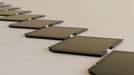 Close up on a tightly packed, perfectly aligned linear array of variously colored SD cards on a simple modernist neutral surface. This image is a 3d render.の写真素材