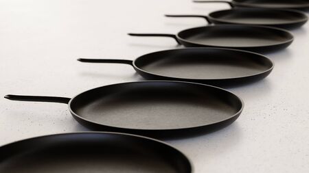 Linear Array of Iron Frying Pans on a Light Gray Surfaceの写真素材