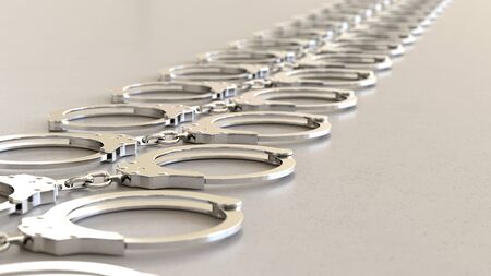 Linear Array of chrome Handcuffss on a Light Gray Surfaceの写真素材