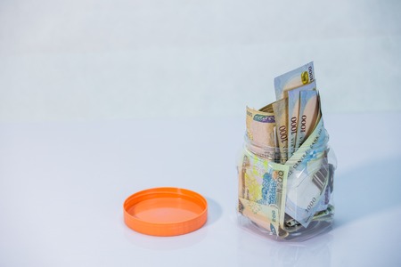 Local currencies and Naira notes in a glass jar - concept of Saving