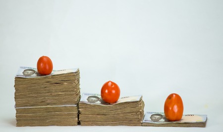Stack of nigeria naira notes on white background wit tomatoesの写真素材