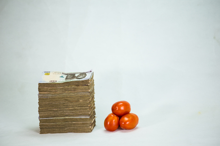 Stack of nigeria naira notes and tomatoes - increase in food commodityの写真素材