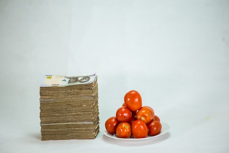 Stack of nigeria naira notes on white background wit tomatoesの写真素材