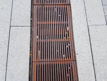 metal drain grate on the ground with small stones in it