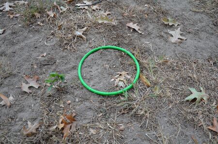 circular green plastic ring in brown grass or lawn with leaves and dirt