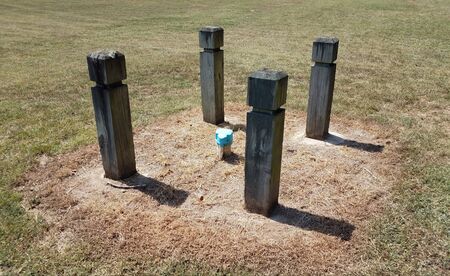 four wooden poles and gas pipe in green grassの写真素材
