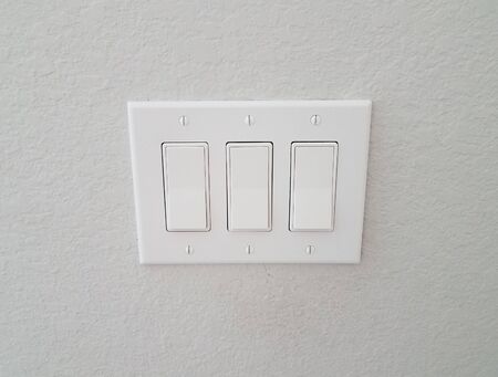 white wall with three buttons or light switches