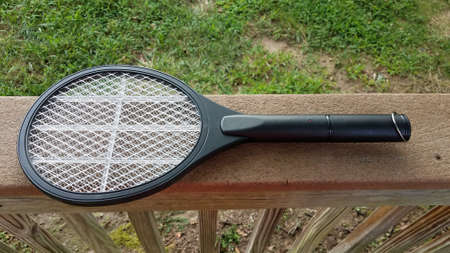 electronic metal tennis racket insect killer on wood railingの写真素材