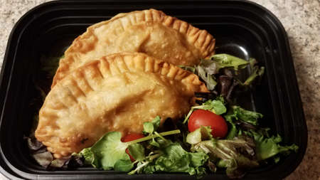 Puerto Rican fried beef turnover and salad in container