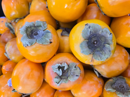 Stack of bright orange persimmons with prominent gray calyxの写真素材