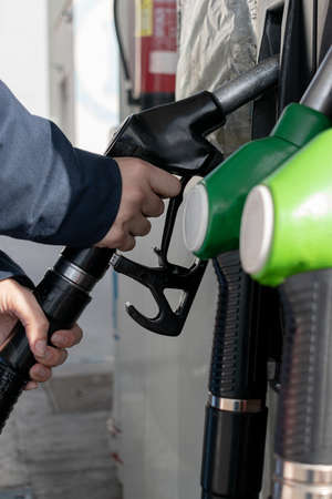 taking the hose from the gas pump to fill the tank of the vehicle
