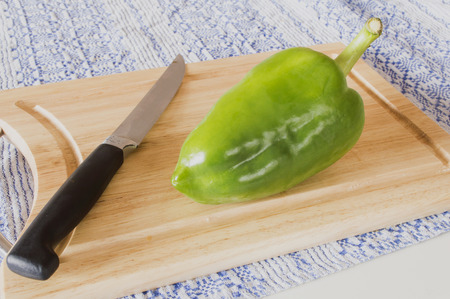Single green pepper and knife on chopping blockの写真素材