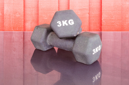 Two black dumbbells on red wood backgroundの写真素材