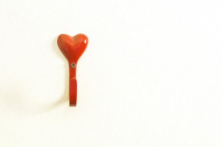 Red  heart plastic wall hook hangers isolated on whiteの写真素材