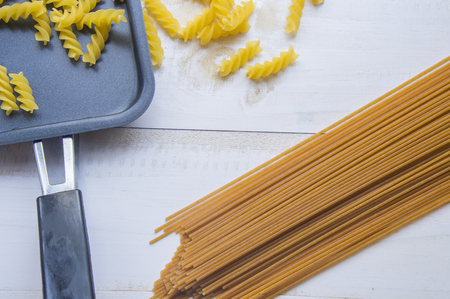 Organic whole wheat bunch of raw italian spaghetti pasta on a white table background, selective focus.の写真素材