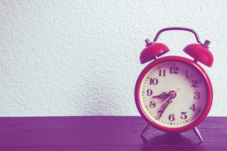 Red clock on wood background.