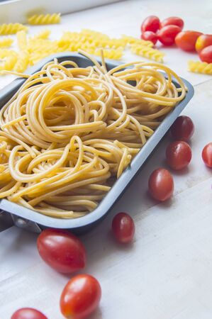 Organic whole wheat bunch of raw italian spaghetti pasta on a white table background, selective focus.の写真素材