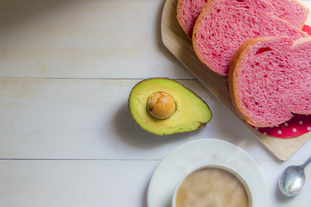 Pink whole wheat bread with espresso coffee and avocado on white woodle.の写真素材