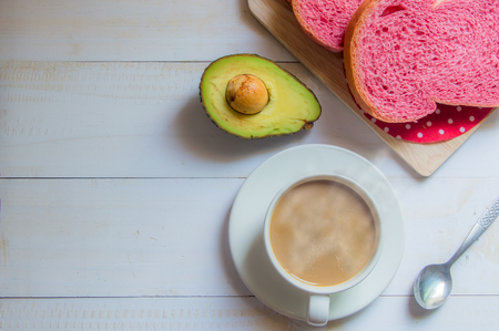 Pink whole wheat bread with espresso coffee and avocado on white woodle.の写真素材
