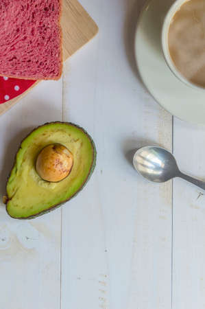 Pink whole wheat bread with espresso coffee and avocado on white woodle.の写真素材
