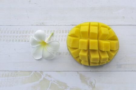 Mango fruit with flower on white wooden background.