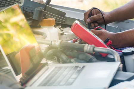 Auto mechanic uses a multimeter voltmeter to check the voltage level in a car battery,Selective focus.の写真素材