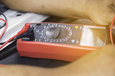 Auto mechanic uses a multimeter voltmeter to check the voltage level in a car battery,Selective focus.の写真素材