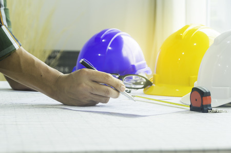 Man of engineers writing at a blueprint for construction on the table. Engineering concept.の写真素材