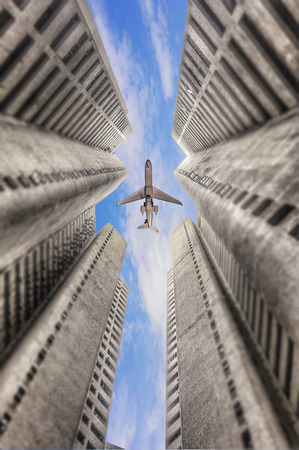 Airplane flying over business skyscrapers in  blue sky background.の写真素材
