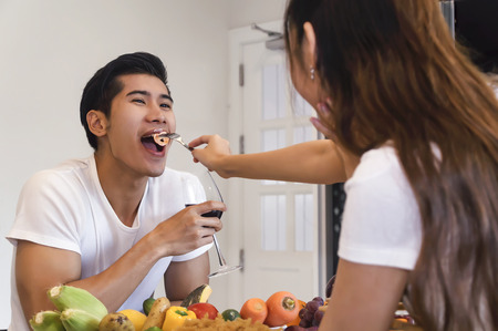 Beautiful asian young couple is looking to cooking in kitchen at home,Happy young handsome man...